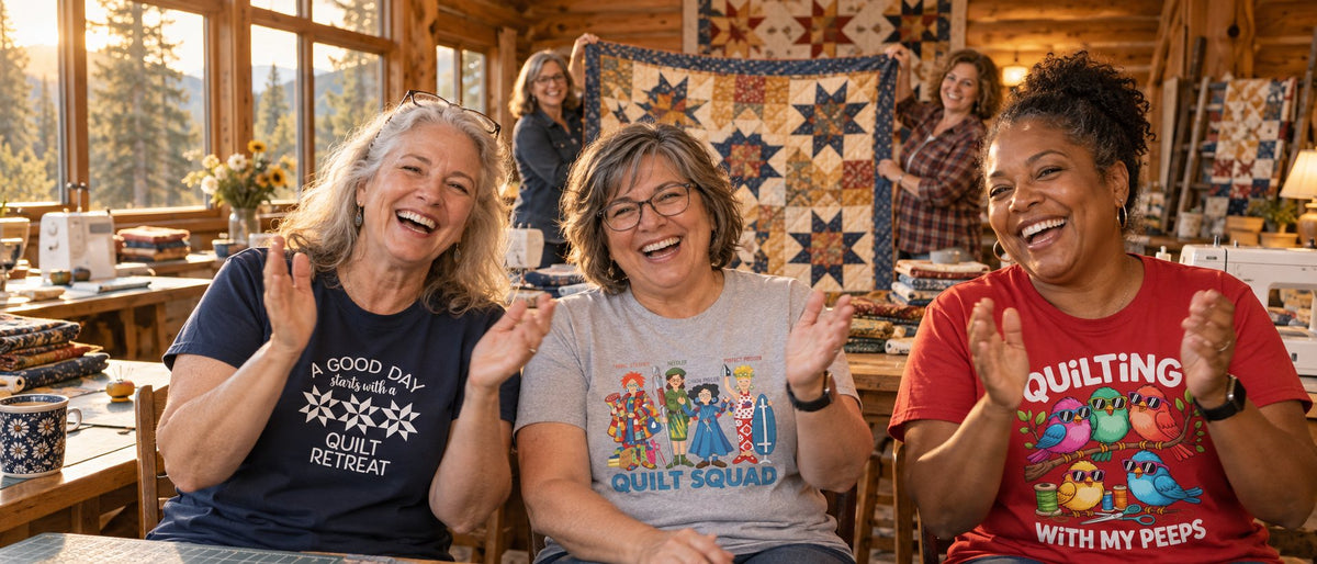 Quilters at a cabin retreat cheering a finished sawtooth-star quilt, wearing The Retreat Quilter tees